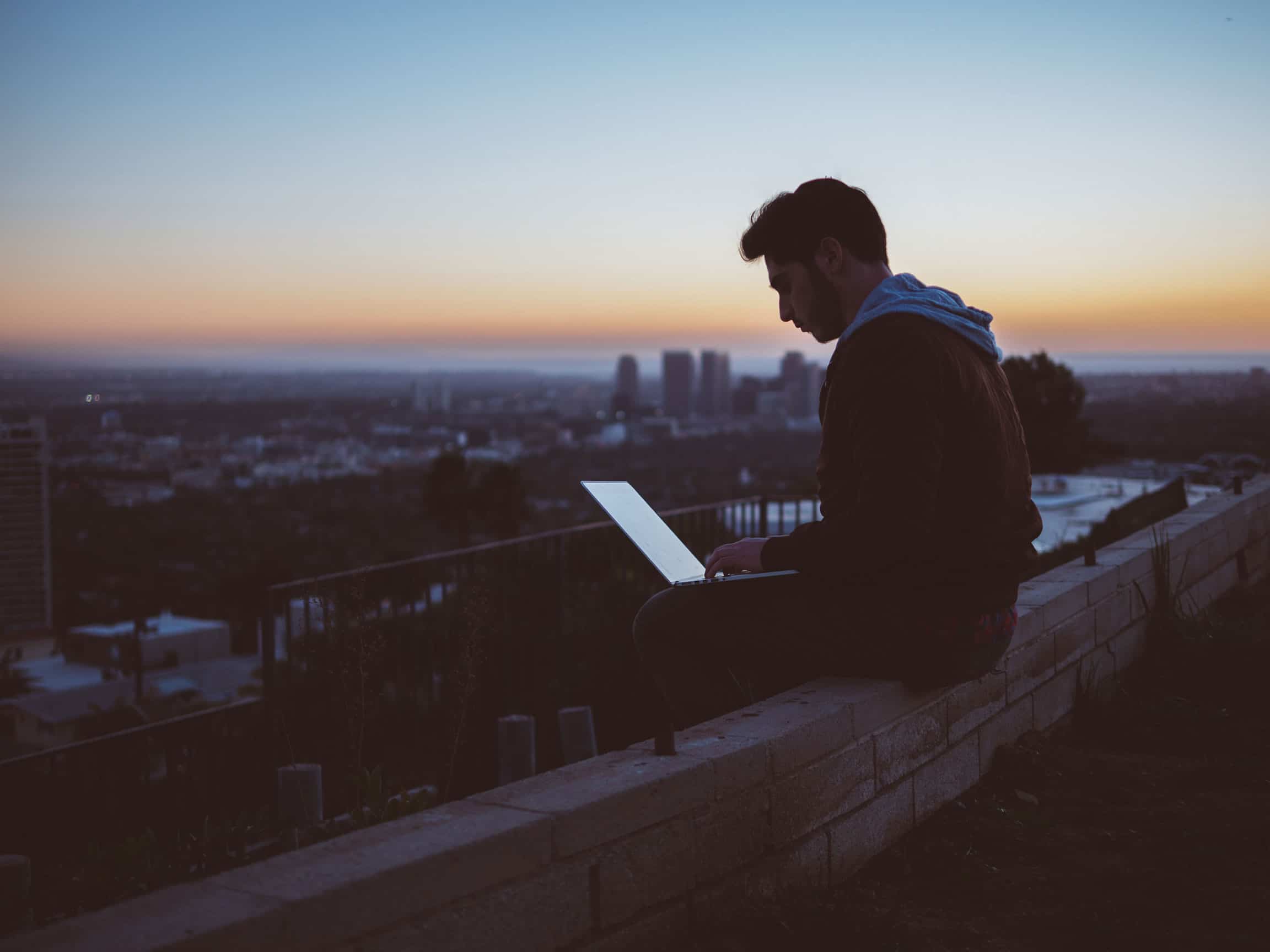 Man sitting with laptop on roof