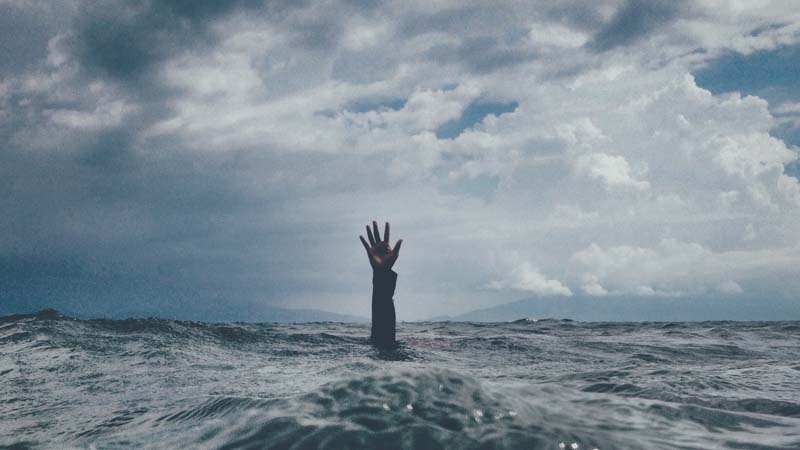 Persons hand above water to illustrate how hard it is to build a web design business when you're super busy